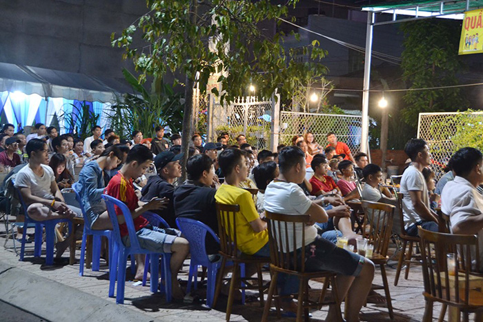 NHM ngồi tràn ra vỉa hè để có được một tầm nhìn ưng ý để xem trận đấu. Ảnh: Trần Anh Tuấn.