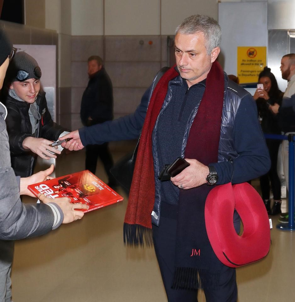 Trên tay Mourinho có đeo chiếc gối hình chữ U màu đỏ, dùng để kê cổ cho đỡ mỏi khi ngồi máy bay. Đây là sản phẩm được nhà tài trợ làm riêng cho Manchester United.