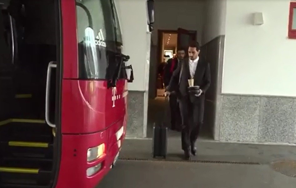 Trên đường ra xe bus để tới sân bay di chuyển sang nước Anh, Mats Hummels gặp phải sự cố dở khóc dở cười. Tay phải anh kéo va-ly, tay trái cầm 2 cái hộp, trên có cốc cà phê rất chông chênh.