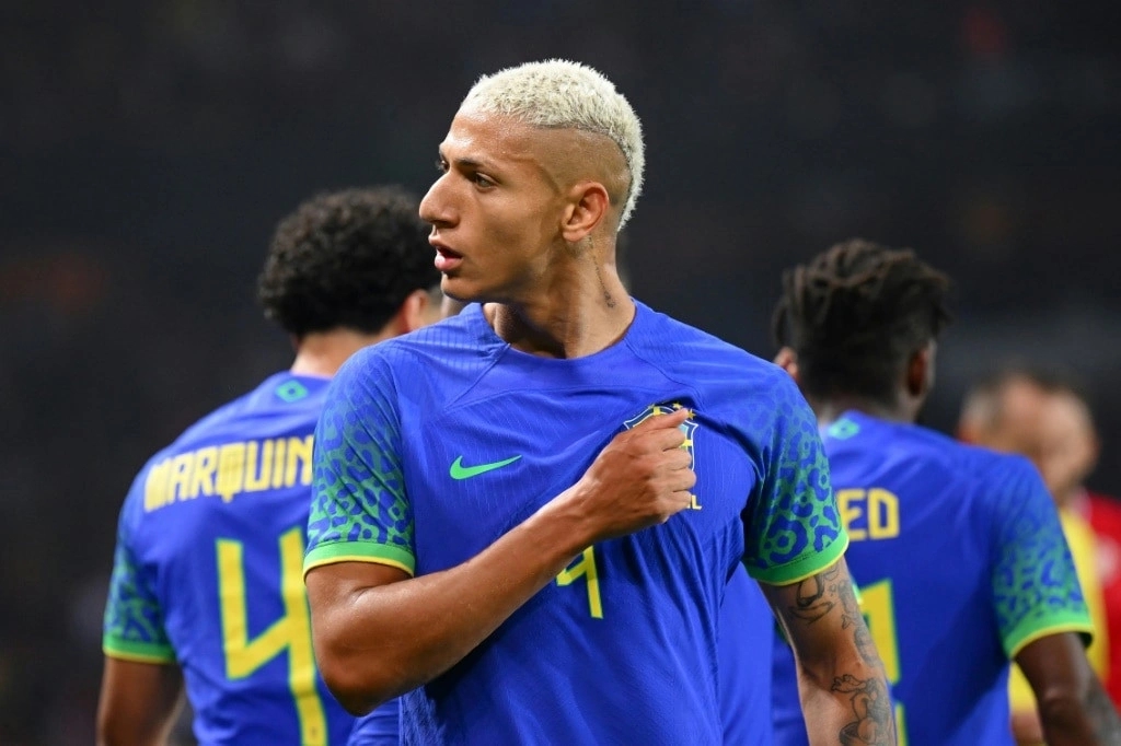 Richarlison vỗ vào logo đội tuyển Brazil với vẻ mặt đầy tự hào.