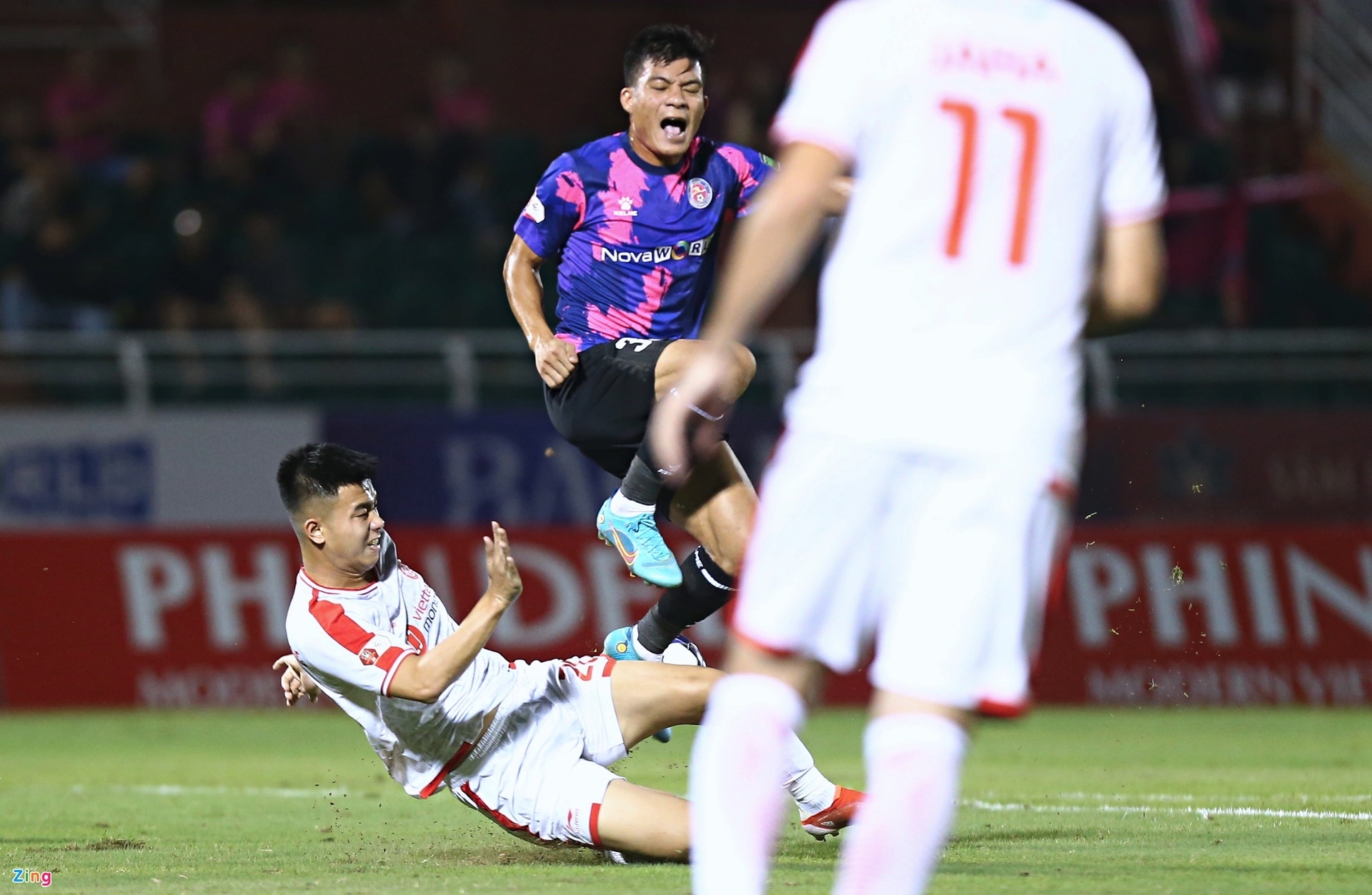 Tấn Tài (áo tím) chủ động kê chân trái vào đùi Hoàng Hùng để tạo ra va chạm. Ảnh: Quang Thịnh.