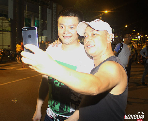 Ngay sau khi trận đấu giữa Sài Gòn và SLNA kết thúc Văn Quyến vẫn bị các fan bắt cóc ra một góc riêng bên ngoài sân vận động để chụp hình lưu niệm. Ảnh: Đình Viên.